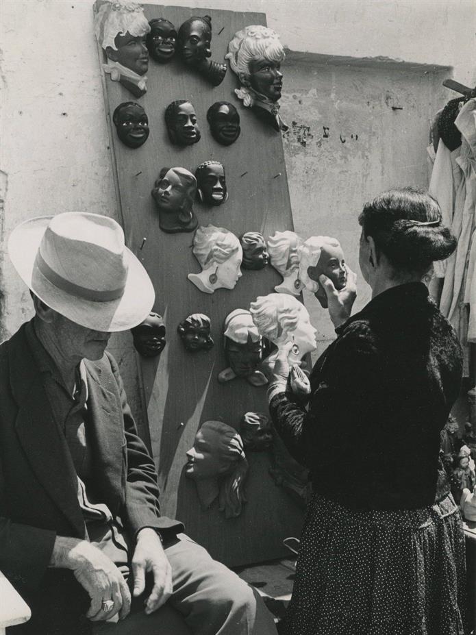 Woman examining small decoration objects in a stall in the market, Israel 1960s Woman examining small decoration objects in a stall in the market, Israel 1960s